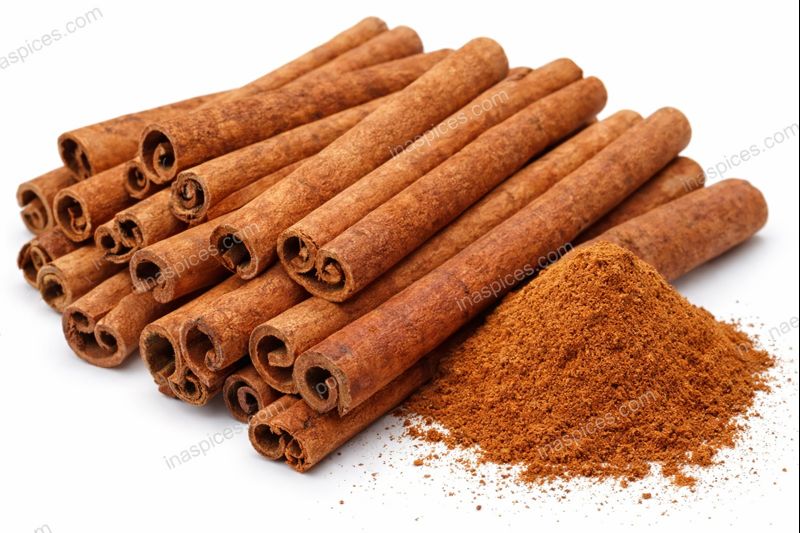 Þurrkuð kanilstöng og malaður kanill á hvítum bakgrunni